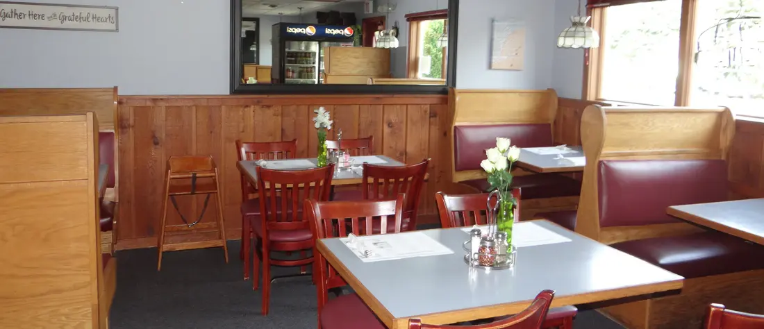The dining room at Family Pizza Restaurant, wooden booths and set tables